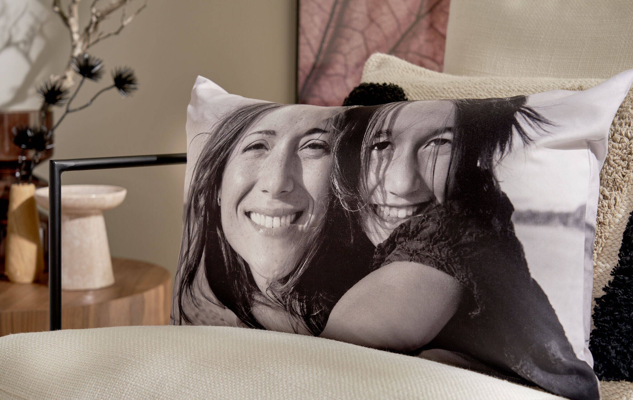 Auf einem Sessel steht ein Fotokissen im Querformat. Darauf ist die Schwarz-Weiß-Aufnahme einer Mutter mit ihrer Tochter zu sehen, die beide in die Kamera lächeln.
