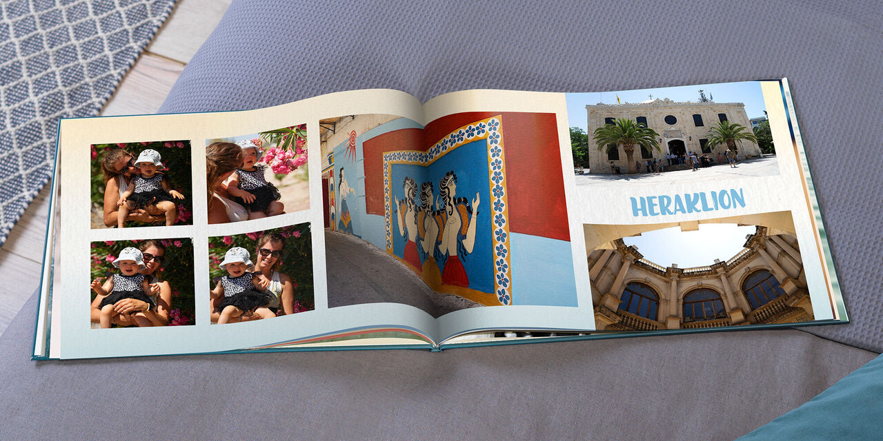 Ein aufgeschlagenes CEWE FOTOBUCH zeigt vier kleine Bilder von Magy und Hannah, drei Fotos von Gebäuden und die Überschrift "HERAKLION".