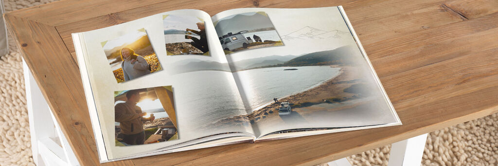 Es ist eine Doppelseite aus einem CEWE FOTOBUCH von Annika und Mathias Koch zu sehen. Das Buch liegt auf einem Tisch. Es zeigt eine Landschaftsaufnahme eines Strandes im Hintergrund und einige Impressioenen als Collage über das Bild verteilt.